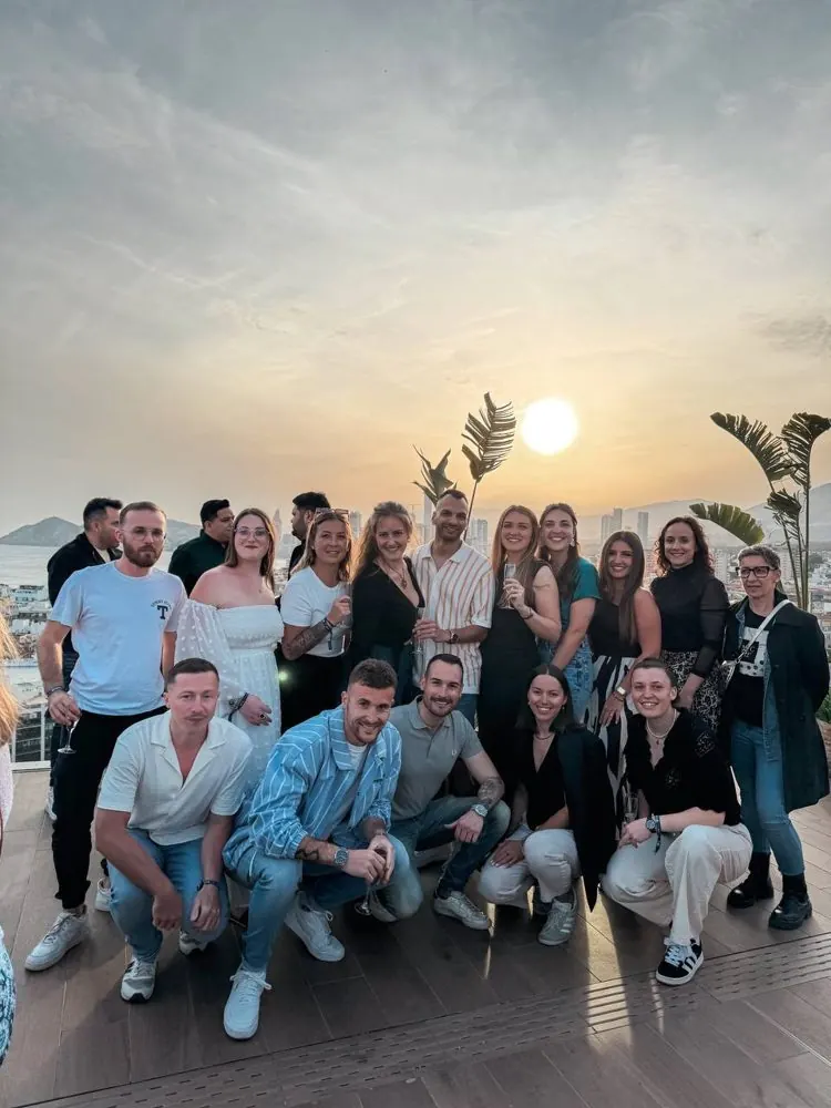 Un groupe de membres sur un rooftop au coucher du soleil, face à la mer